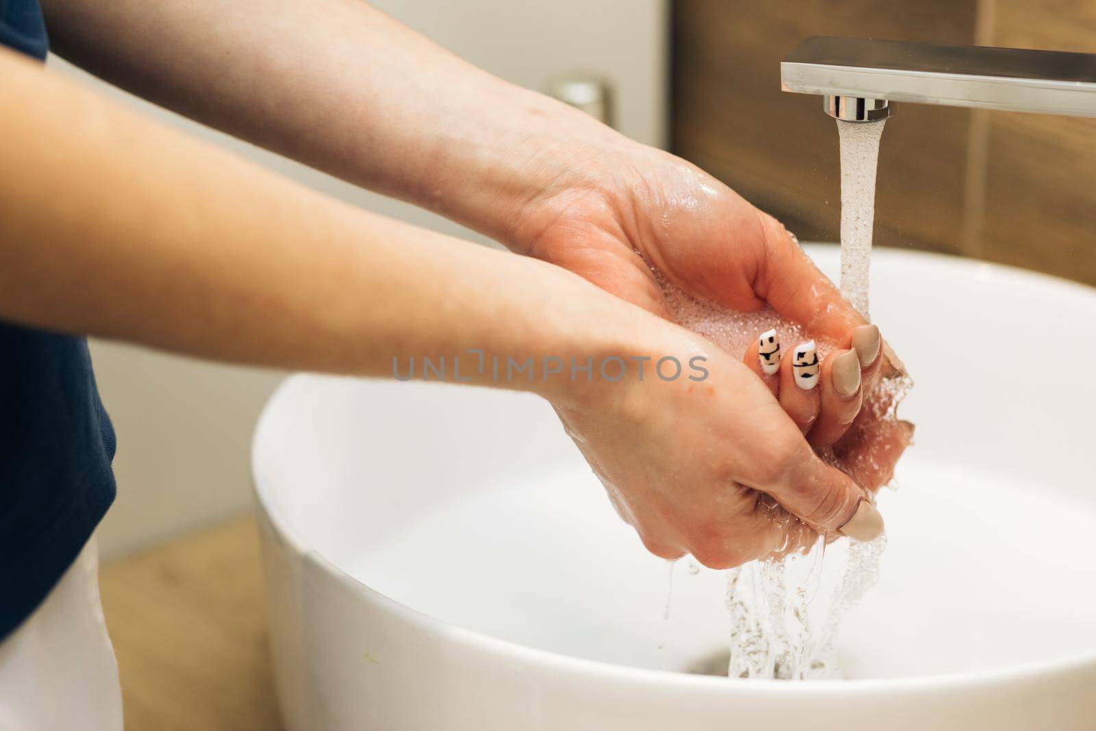 Hands of woman wash their hands in a sink to wash the skin and water flows through the hands. Concept of health, cleaning and preventing germs and coronavirus from contacting hands