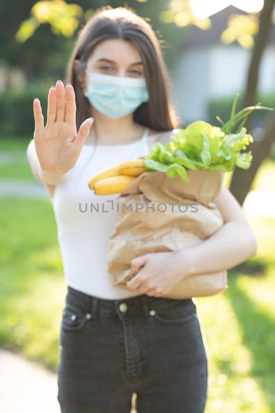 Portrait of a young woman wearing protective mask makes stop sign with hand, saying no, expressing restriction. Concept health and safety, N1H1 coronavirus quarantine, virus protection by uflypro