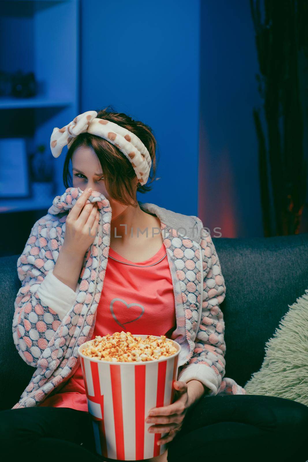 Woman cry while watching a very moving movie with popcorn at night.