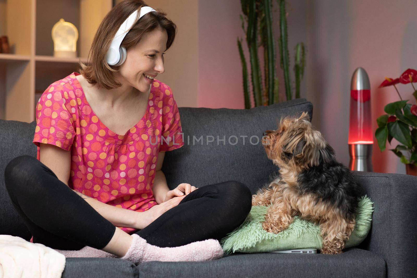 Young woman listening yo music on smart phone, moving to the rythm while sitting on sofa. by uflypro