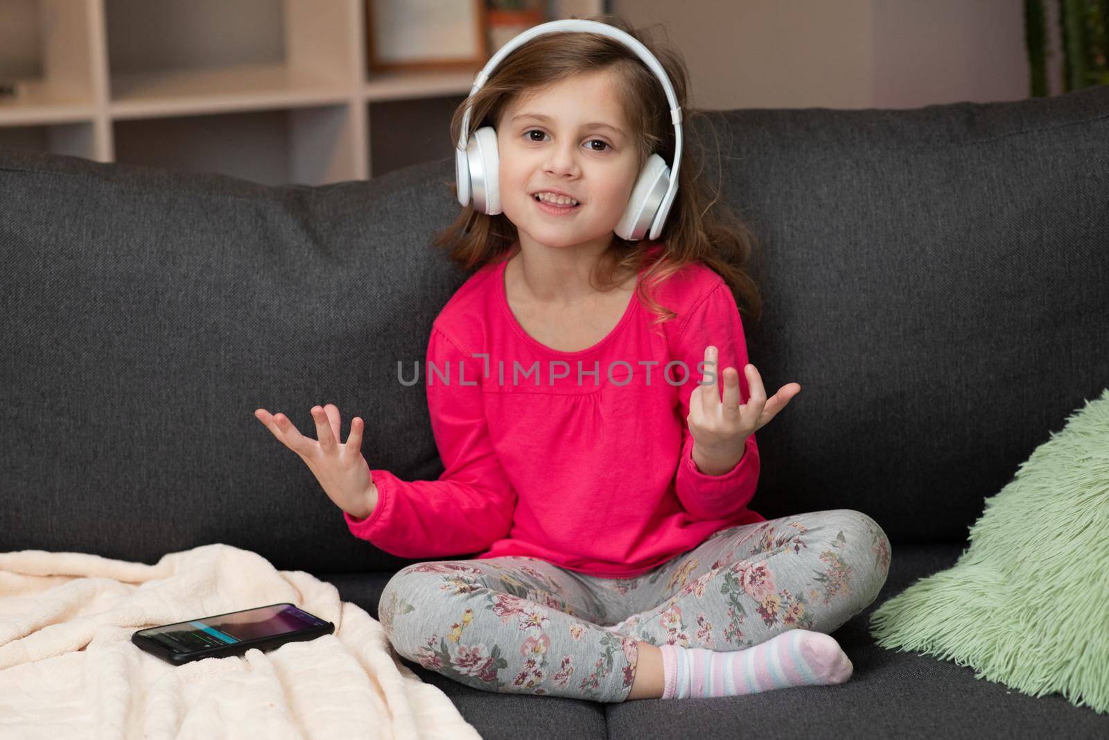 Funny little girl in wireless headphones dancing singing and moving to the rythm. Little girl wearing headphones. Kid in headphones. Happy little girl listening to music with headphones by uflypro