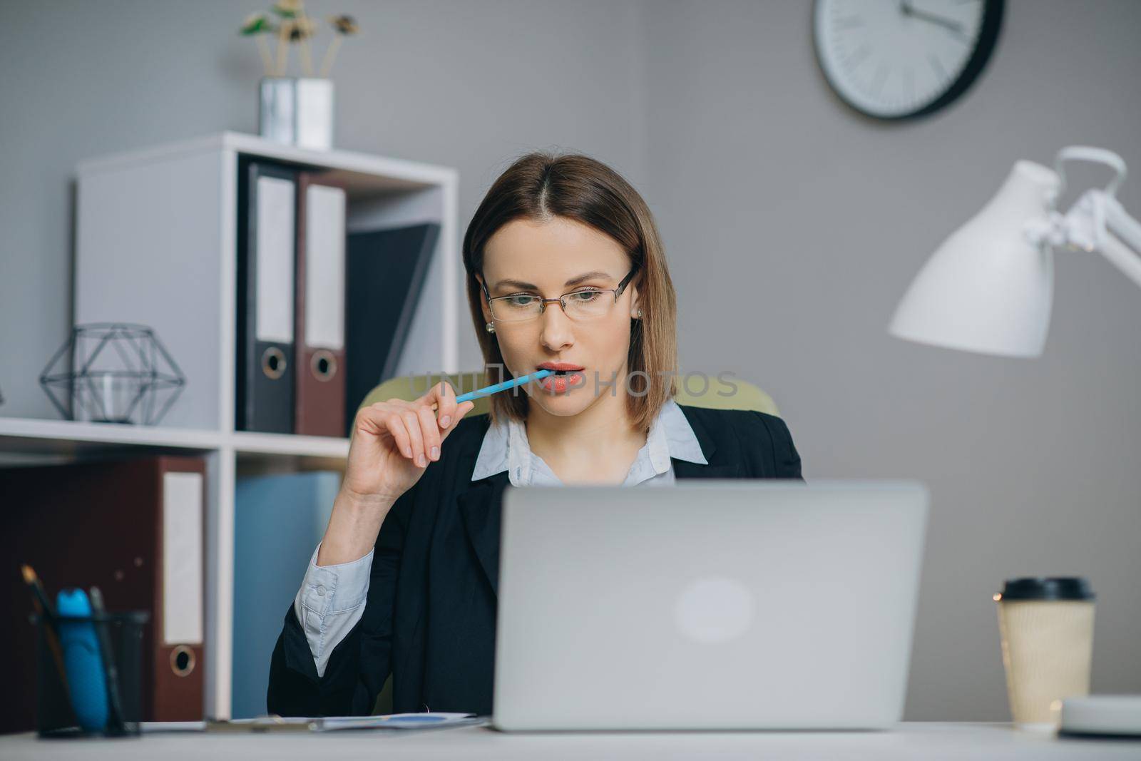 Attractive woman in eye glasses enjoying her favourite freelance job working in home on laptop computer. Female freelancer using netbook and writing ideas in notepad by uflypro