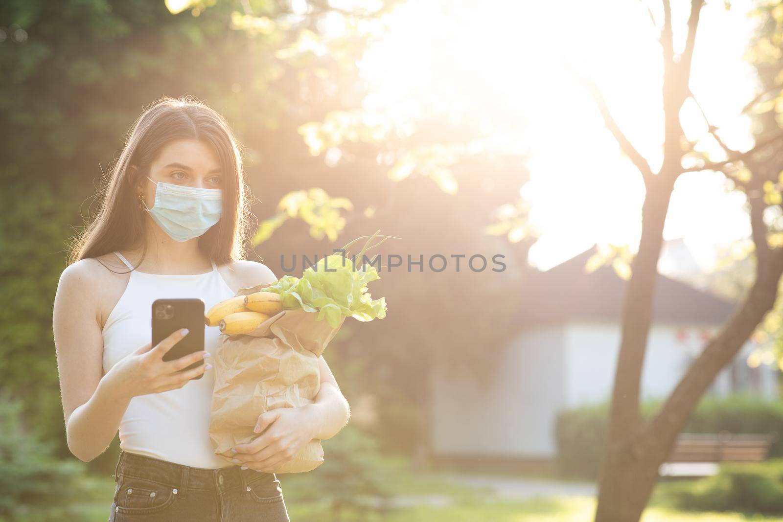 Pandemic. Social distancing. Food delivery. Woman wearing face masks in prevention of coronavirus during quarantine. Woman Using the Mobile Phone.