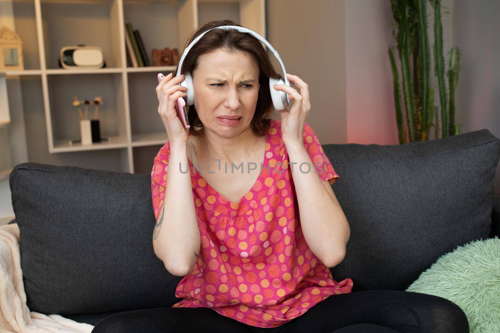 Girl with Headphones Unhappy. Beautiful girl wearing headphones listening to music with angry face, negative rejection concept