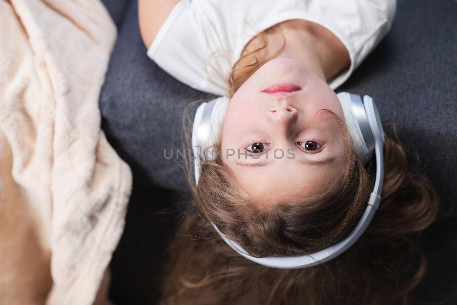 Funny little girl in wireless headphones dancing singing and moving to the rythm. Little girl wearing headphones. Kid in headphones. Happy little girl listening to music with headphones by uflypro