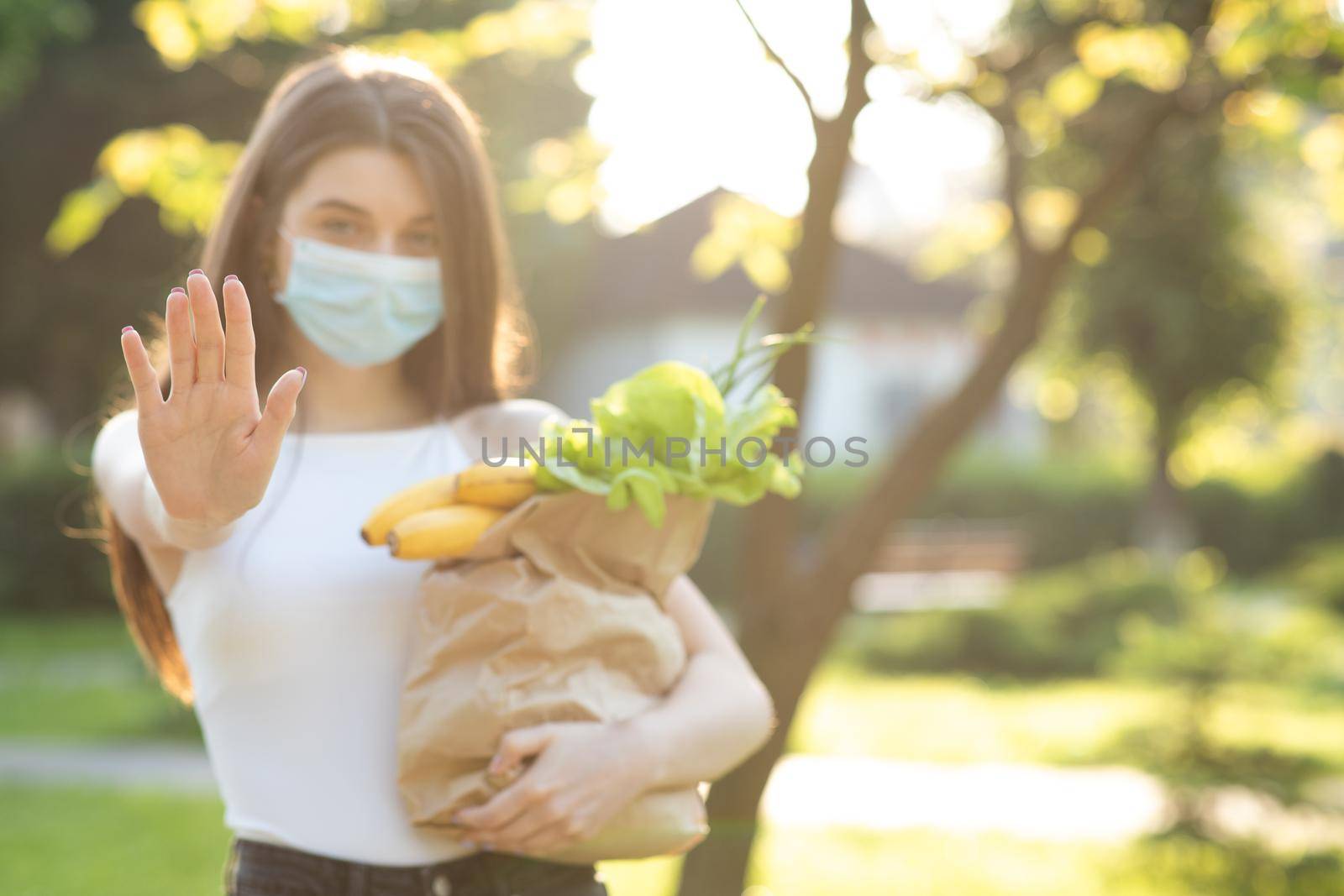 Young woman wearing protective mask makes stop sign with hand, saying no, expressing restriction. Concept health and safety, N1H1 coronavirus quarantine, virus protection by uflypro