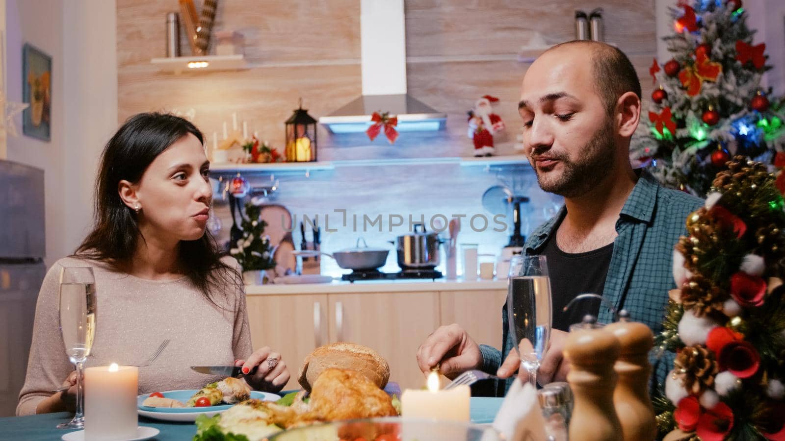 Man and woman celebrating christmas with festive dinner, enjoying traitional meal and drinking alcohol. Couple eating chicken and having glasses of champagne while chatting on holiday