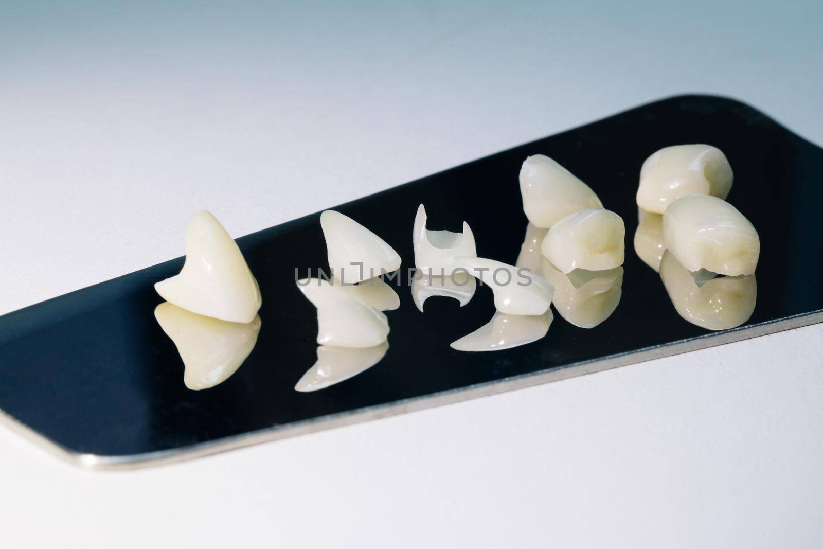 Ceramic tooth with a totally wite background. Ceramic teeth with the veneers. Free metal ceramic teeth by uflypro