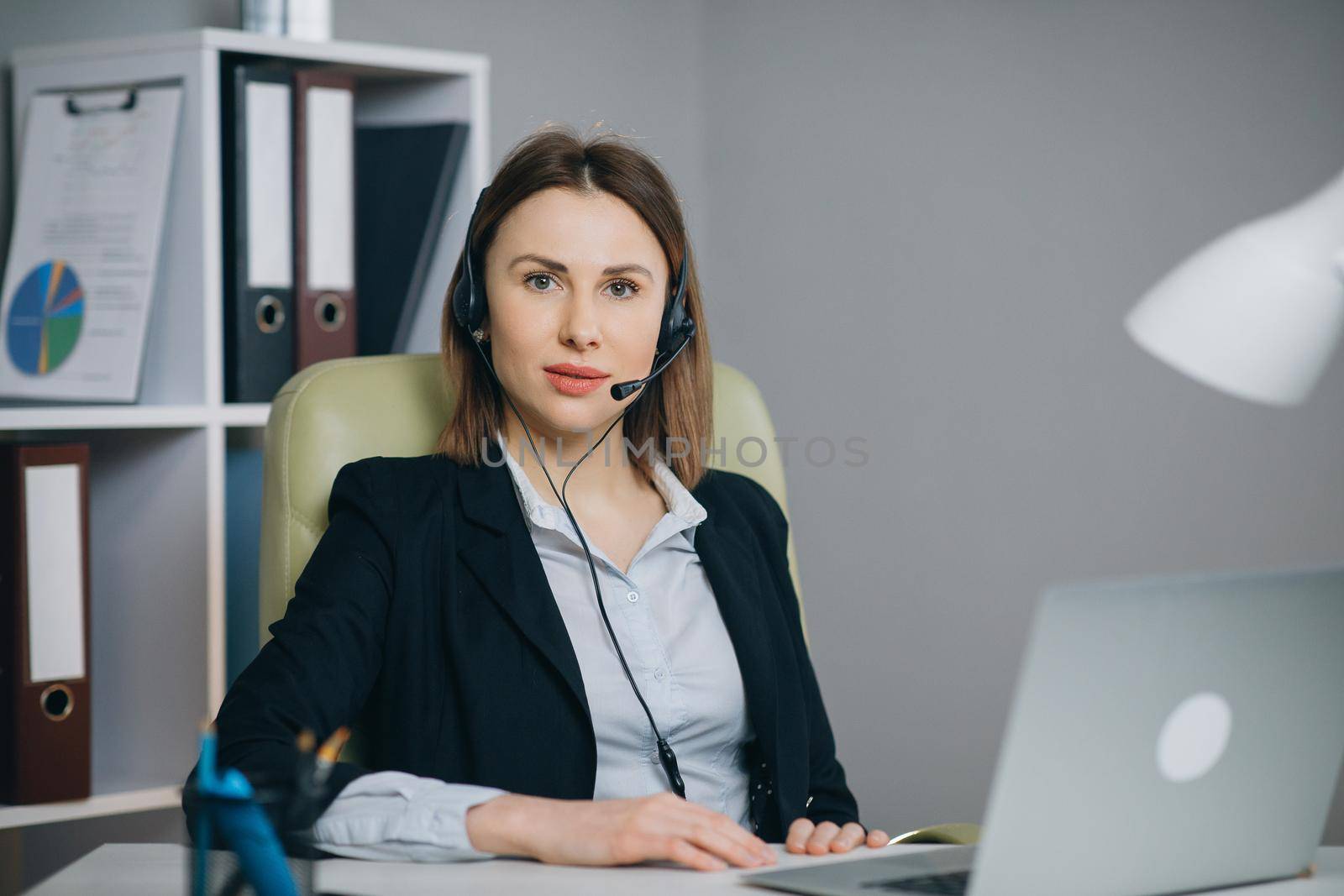 Businesswoman in Headphones Holding Paper Financial Report talk at Webcam make video call in office, business coach looking at camera speak show statistics explain marketing strategy for client