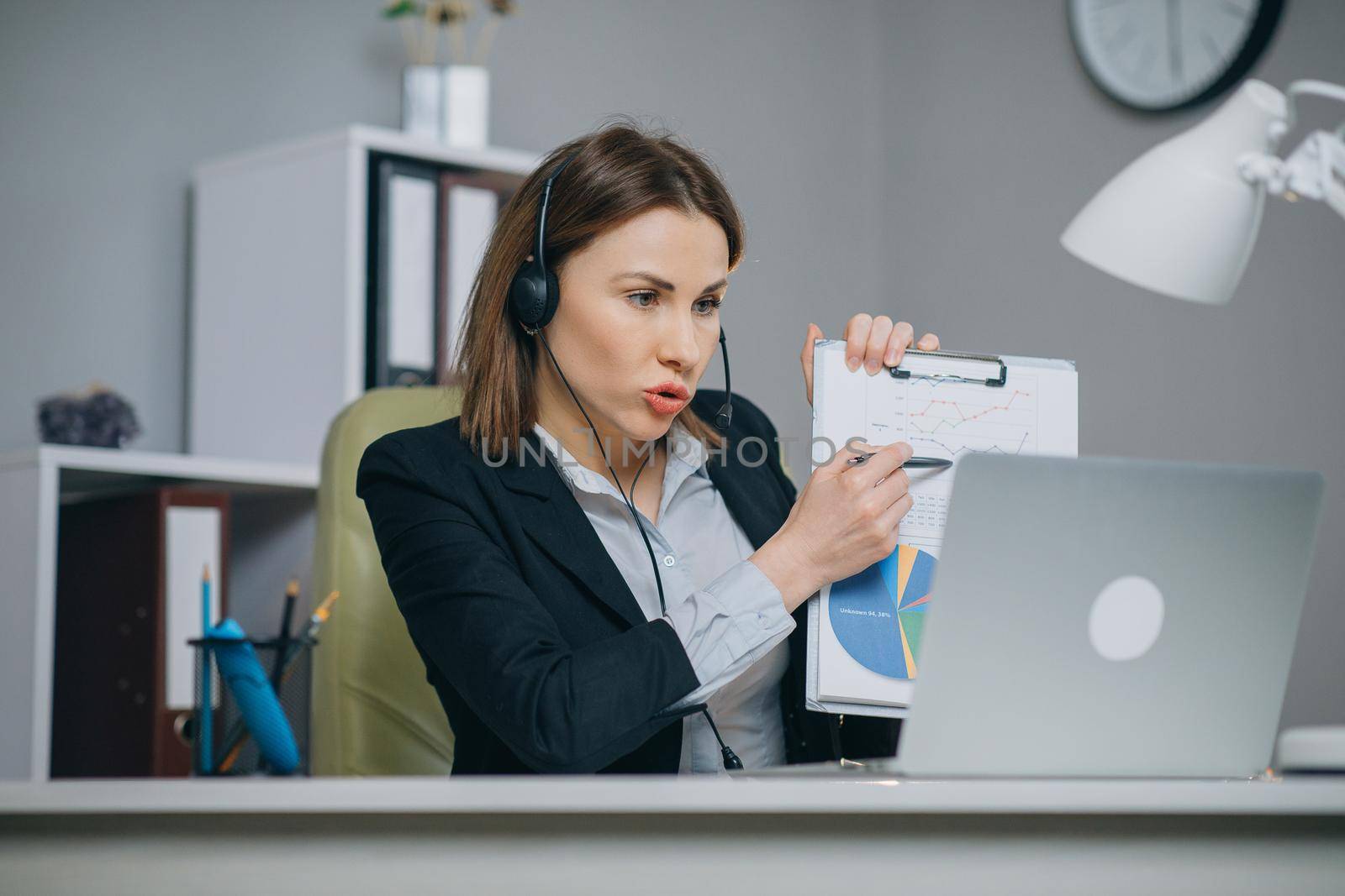 Businesswoman Holding Paper Financial Report Talk at Webcam make Video Call in Office, Business Coach Looking at Camera Speak Show Statistics Explain Marketing Strategy for Client, online training