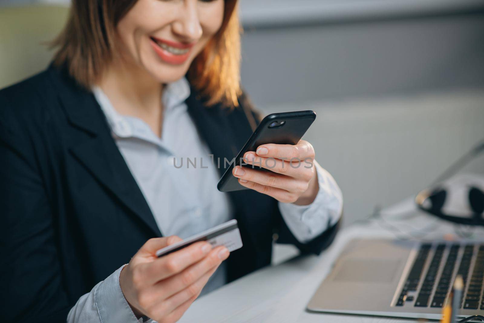 Happy and Smiling Woman Making a Card Payment through Mobile Phone to Pay Bills. An Attractive Girl Putting Debit or Credit Card Details on a Smartphone or Cellphone to Make Online Transaction by uflypro