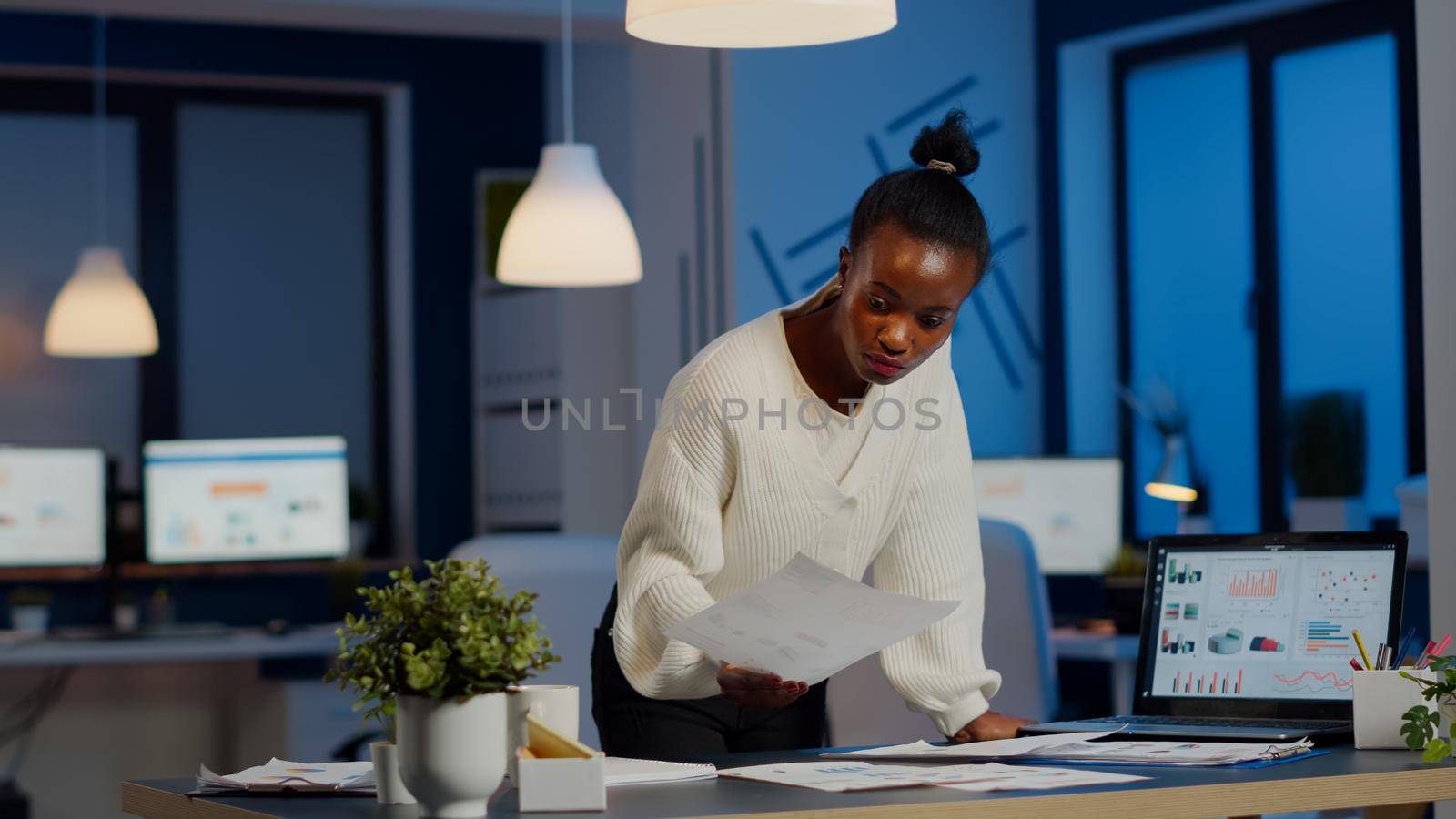 African manager woman working with financial documents standing at desk by DCStudio