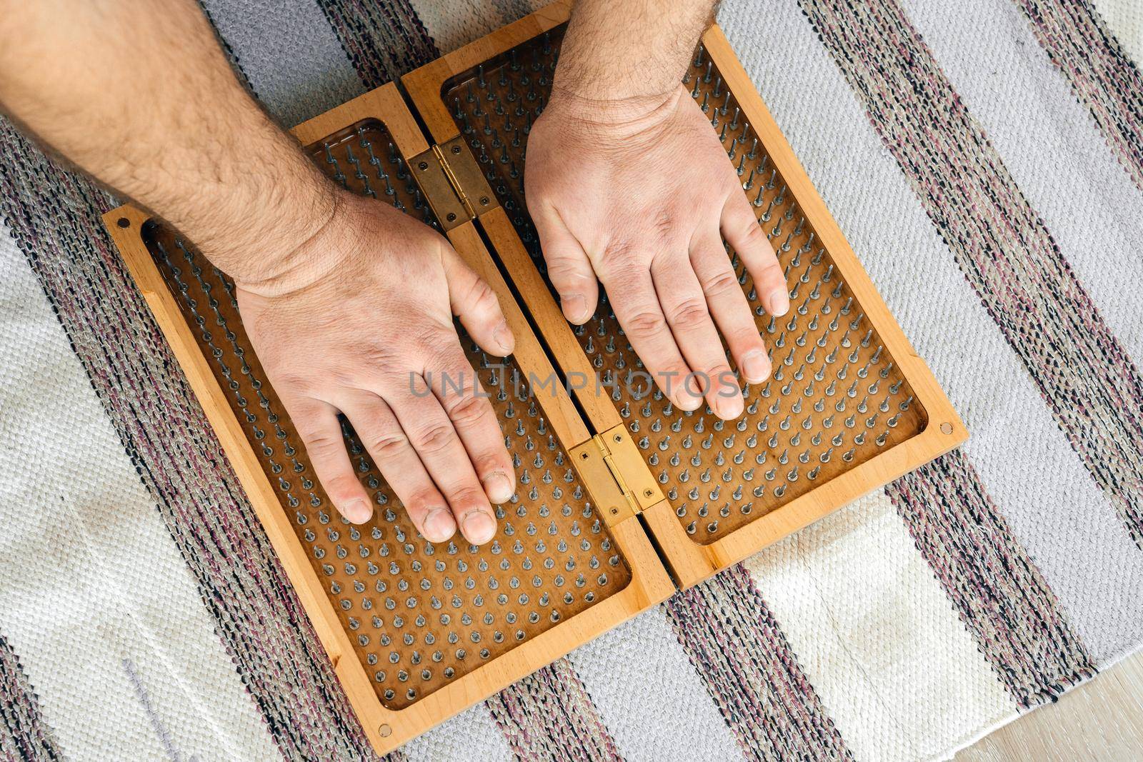 Man touching yoga wooden sadhu board with sharp nails in yoga class