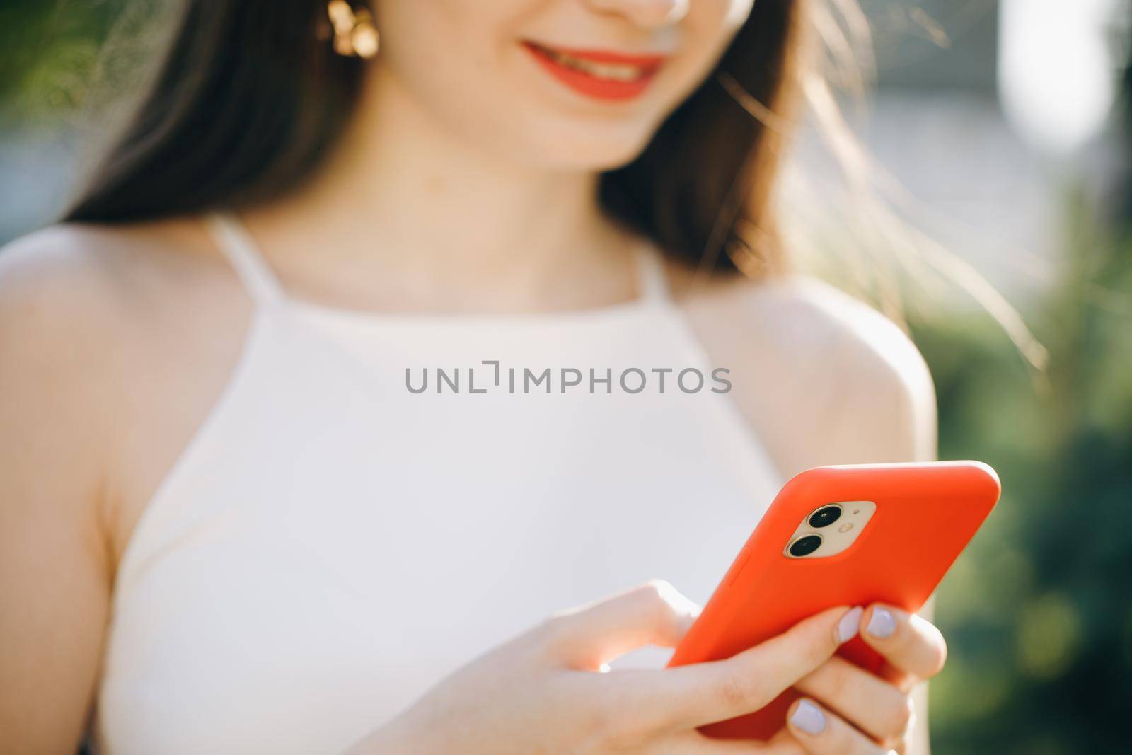 Girl Hands holding smartphone. Woman Using Smartphone in Beautiful Green Park. Technology outdoors.