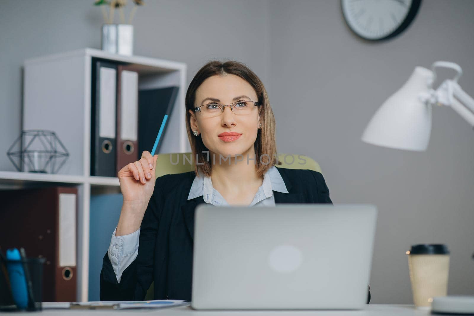 Attractive woman in eye glasses enjoying her favourite freelance job working in home on laptop computer. Female freelancer using netbook and writing ideas in notepad