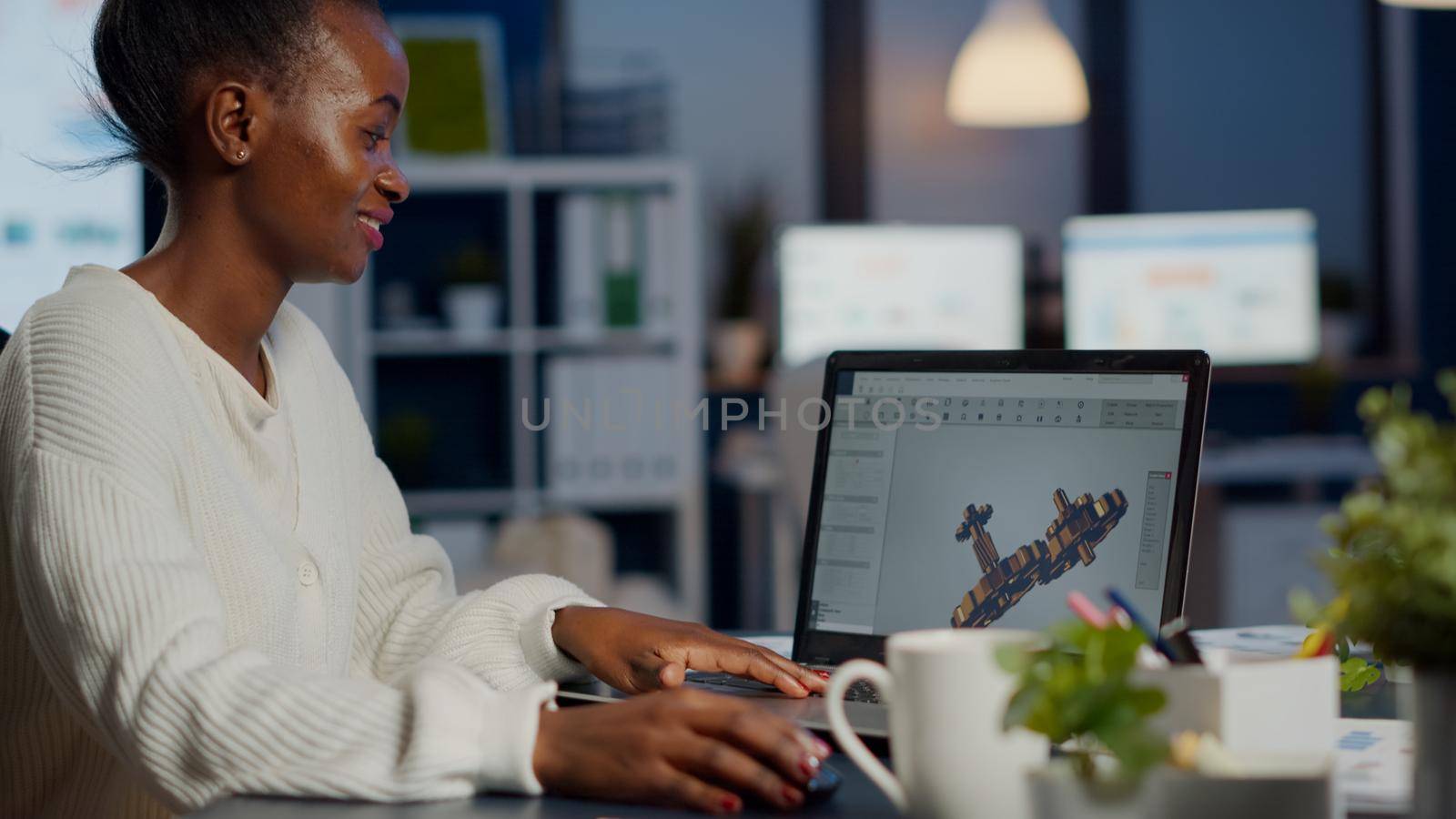 Black woman architect working in modern cad program overtime sitting at desk in start-up business office. Industrial employee studying prototype idea on laptop showing cad software on device display