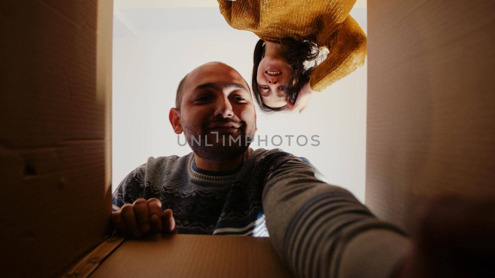 POV of festive couple taking out christmas decorations from box for holiday celebration. People opening package with ornaments and garlands preparing for seasonal winter festivity.