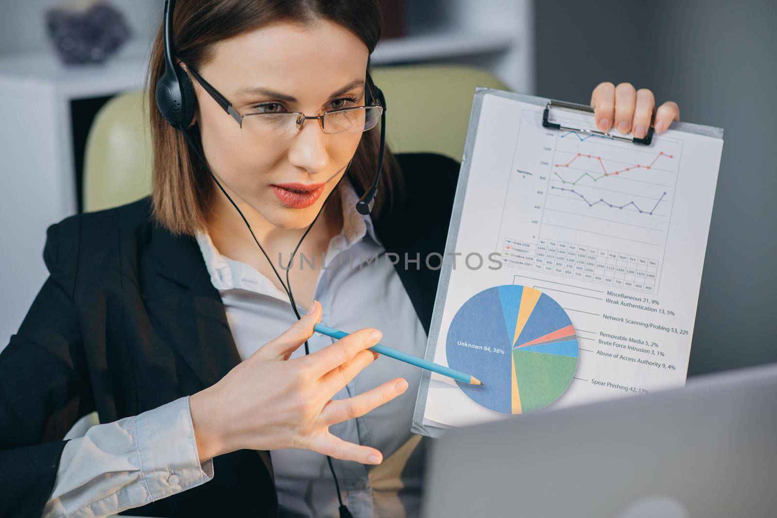 Businesswoman in Headphones Holding Paper Financial Report talk at Webcam make video call in office, business coach looking at camera speak show statistics explain marketing strategy for client.