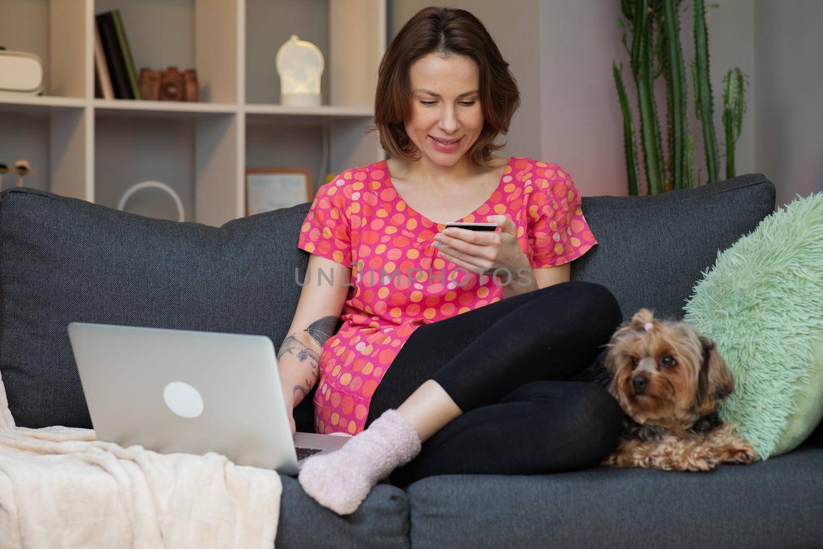 Beautiful woman are buying online with a credit card and smile while sitting on the sofa at home. Woman are using laptop and doing online transactions, Past the internet