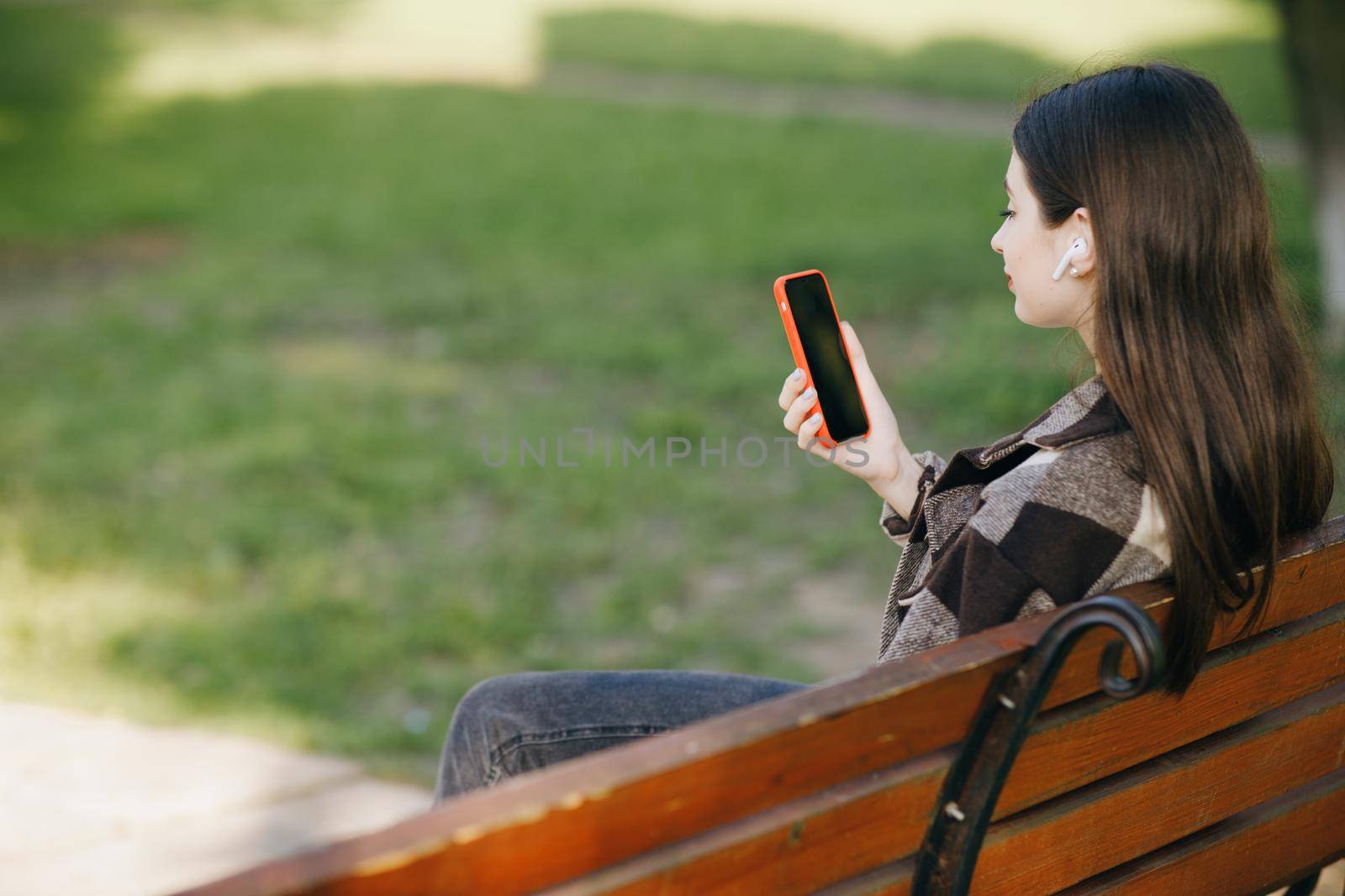 Girl using mobile smart phone in the park. Internet, using smartphone, fashion model, post social network concept.