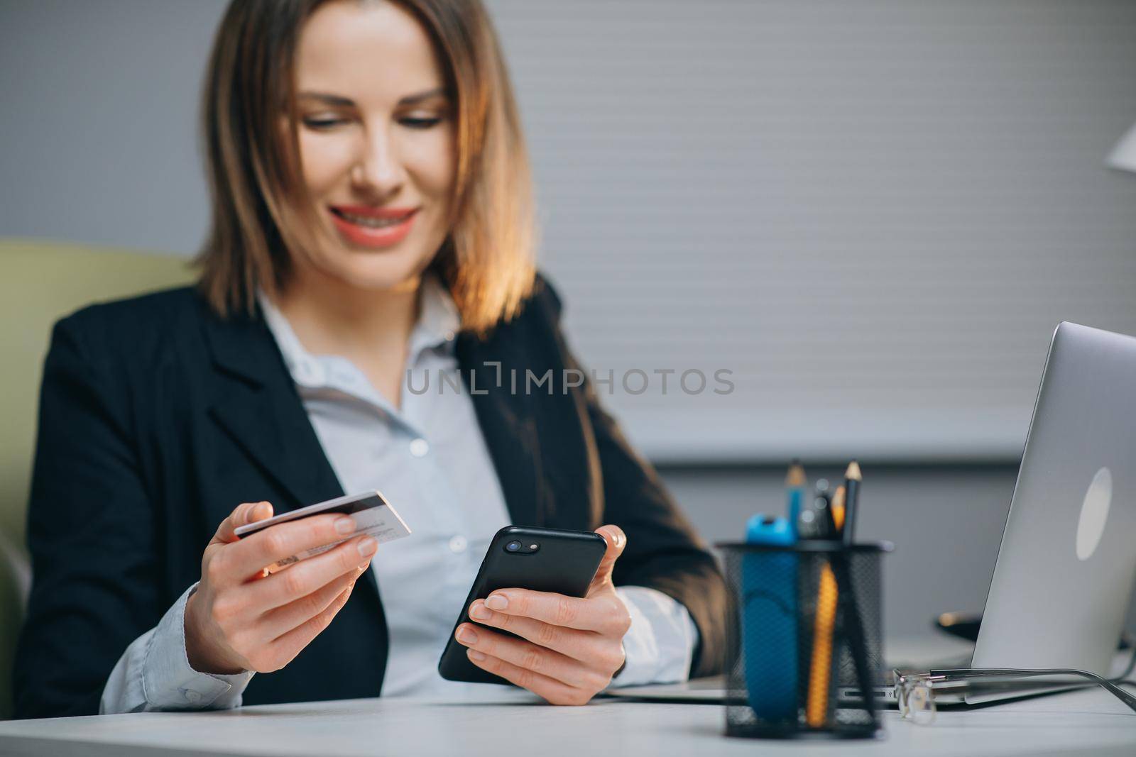 Woman Making a Card Payment through Mobile Phone to Pay Bills. An Attractive Girl Putting Debit or Credit Card Details on a Smartphone or Cellphone to Make Online Transaction by uflypro