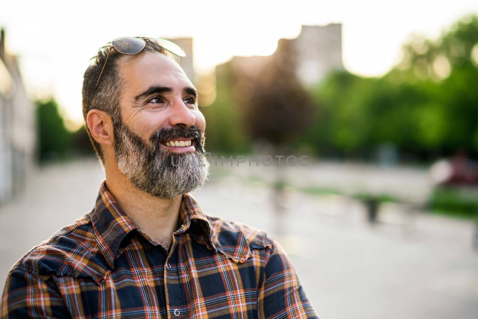 Portrait of modern businessman with beard standing on the city street