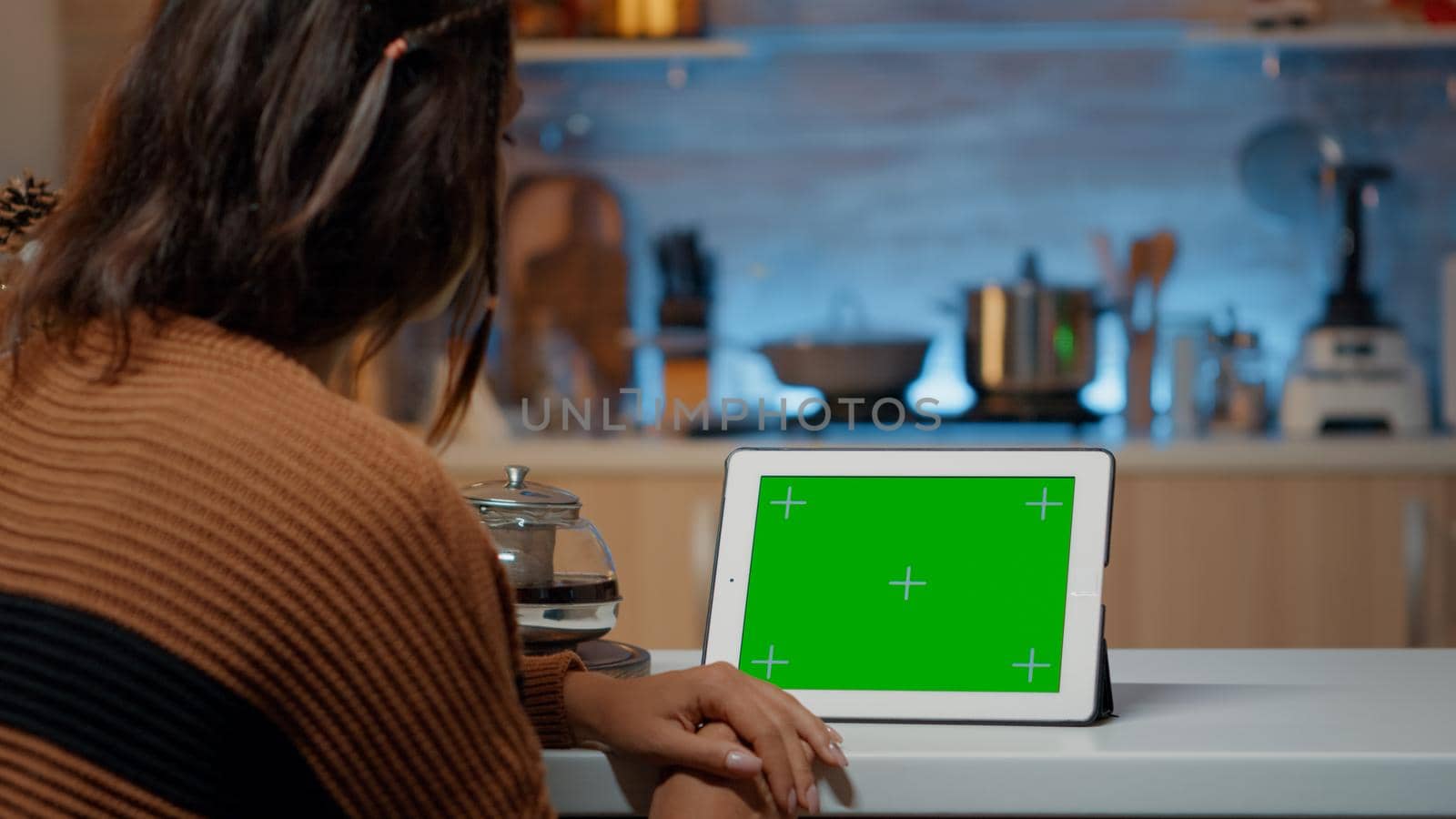 Festive woman looking at green screen display on tablet in decorated kitchen for christmas eve celebration party. Young person using digital technology device to relax at home