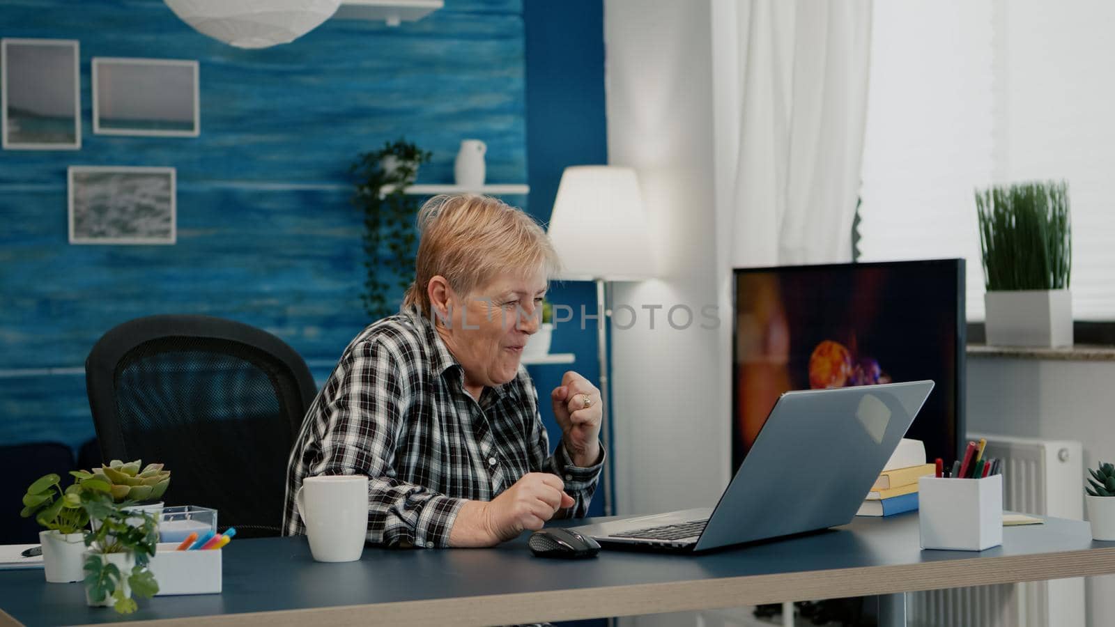 Old woman receving good news on laptop working from home by DCStudio
