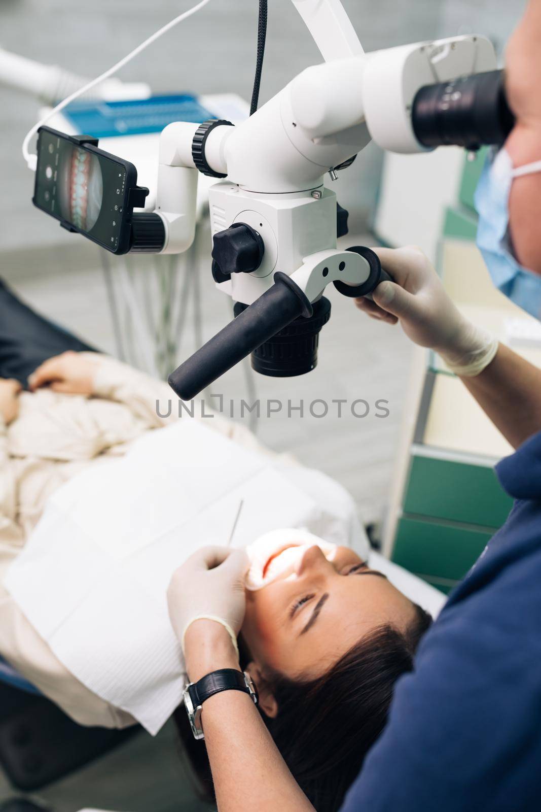 Close-up of a dentist using microscope. Modern equipment microscope in dental office. Doctor dentist using dental microscope in modern dental office. The endodontist is treating canals by uflypro