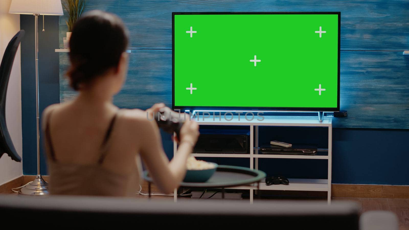 Young woman using controller on green screen on tv by DCStudio