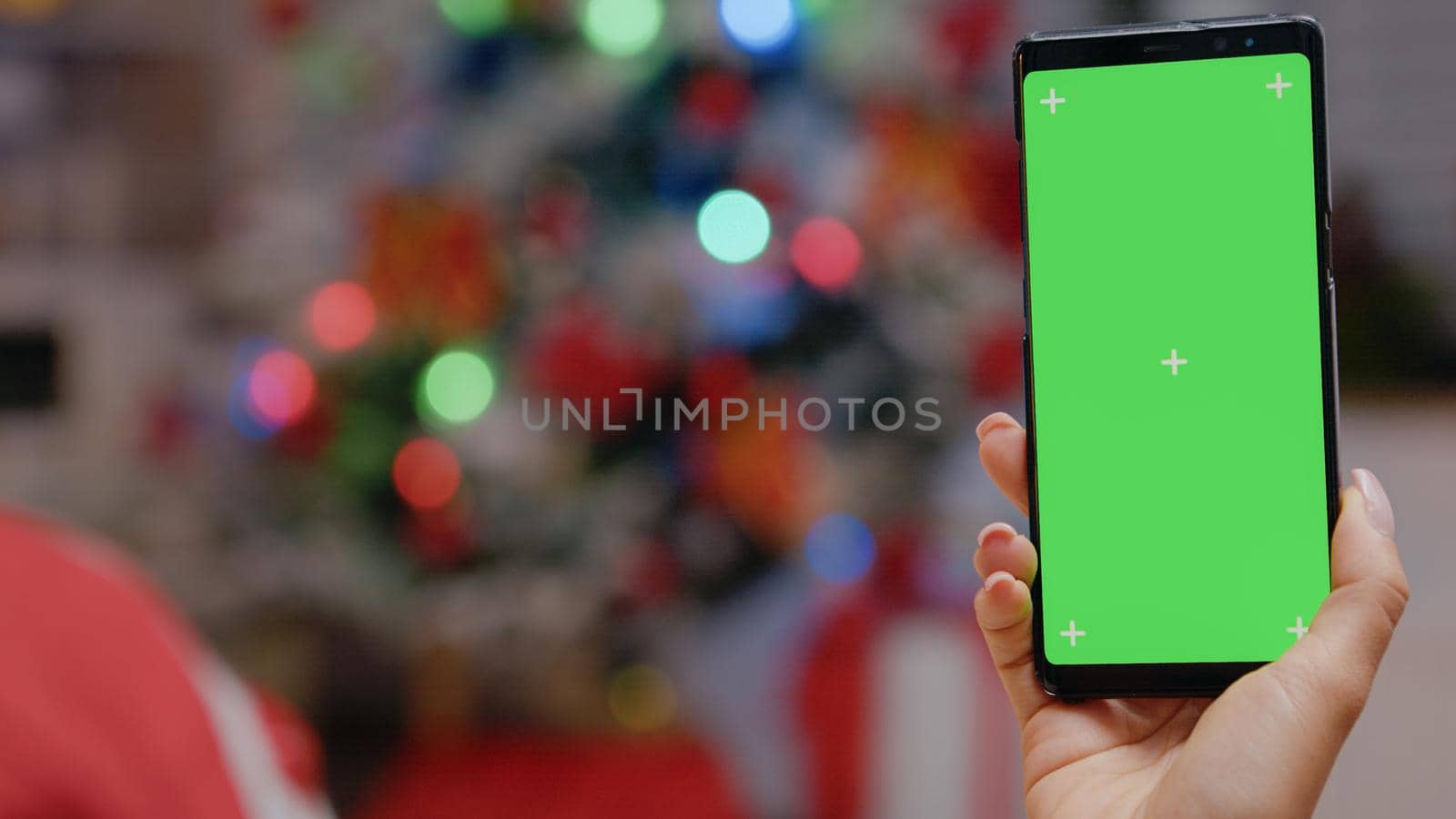 Close up of hand vertically holding smartphone with green screen by DCStudio