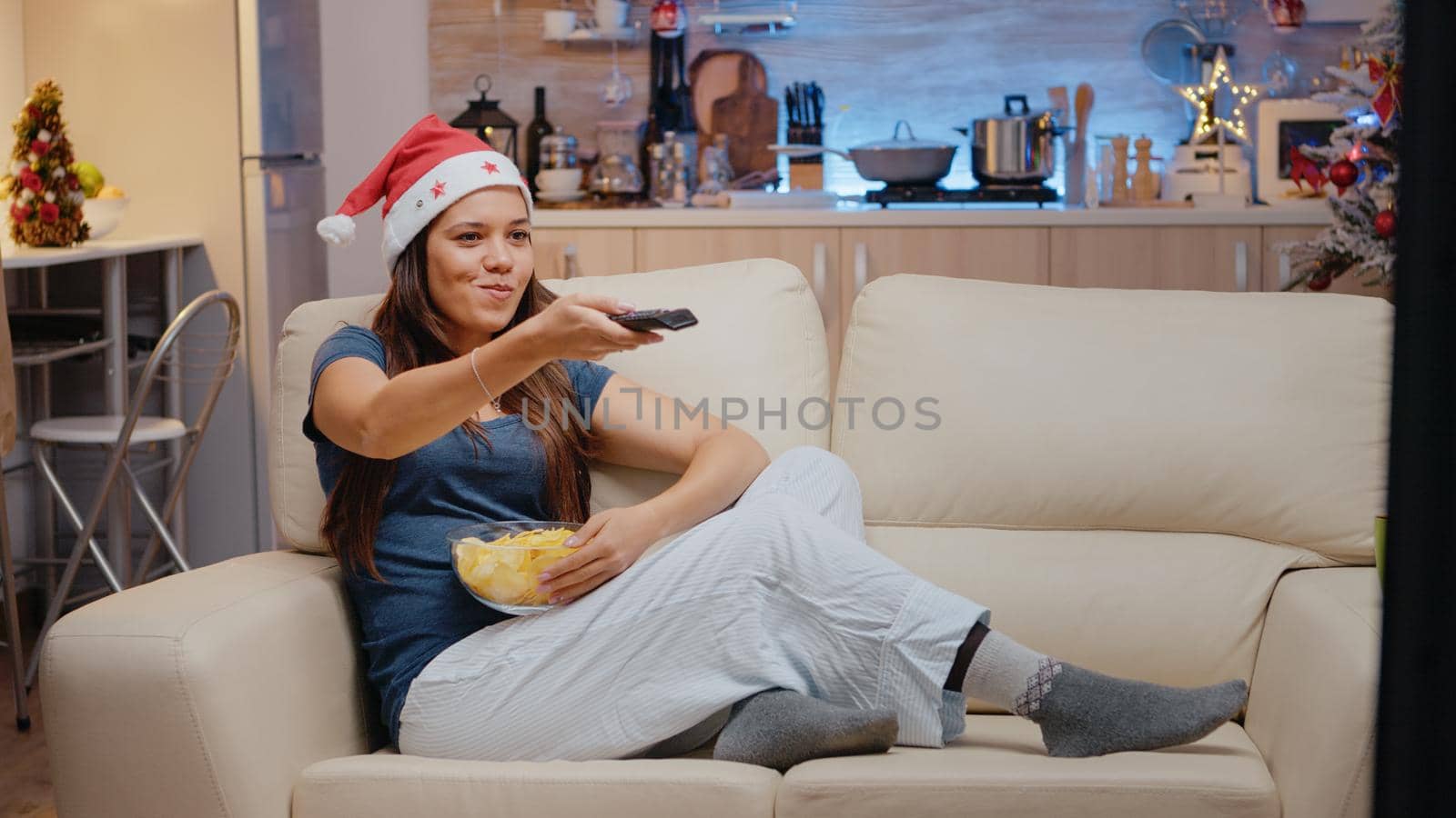 Festive woman wearing santa hat and watching comedy on TV by DCStudio