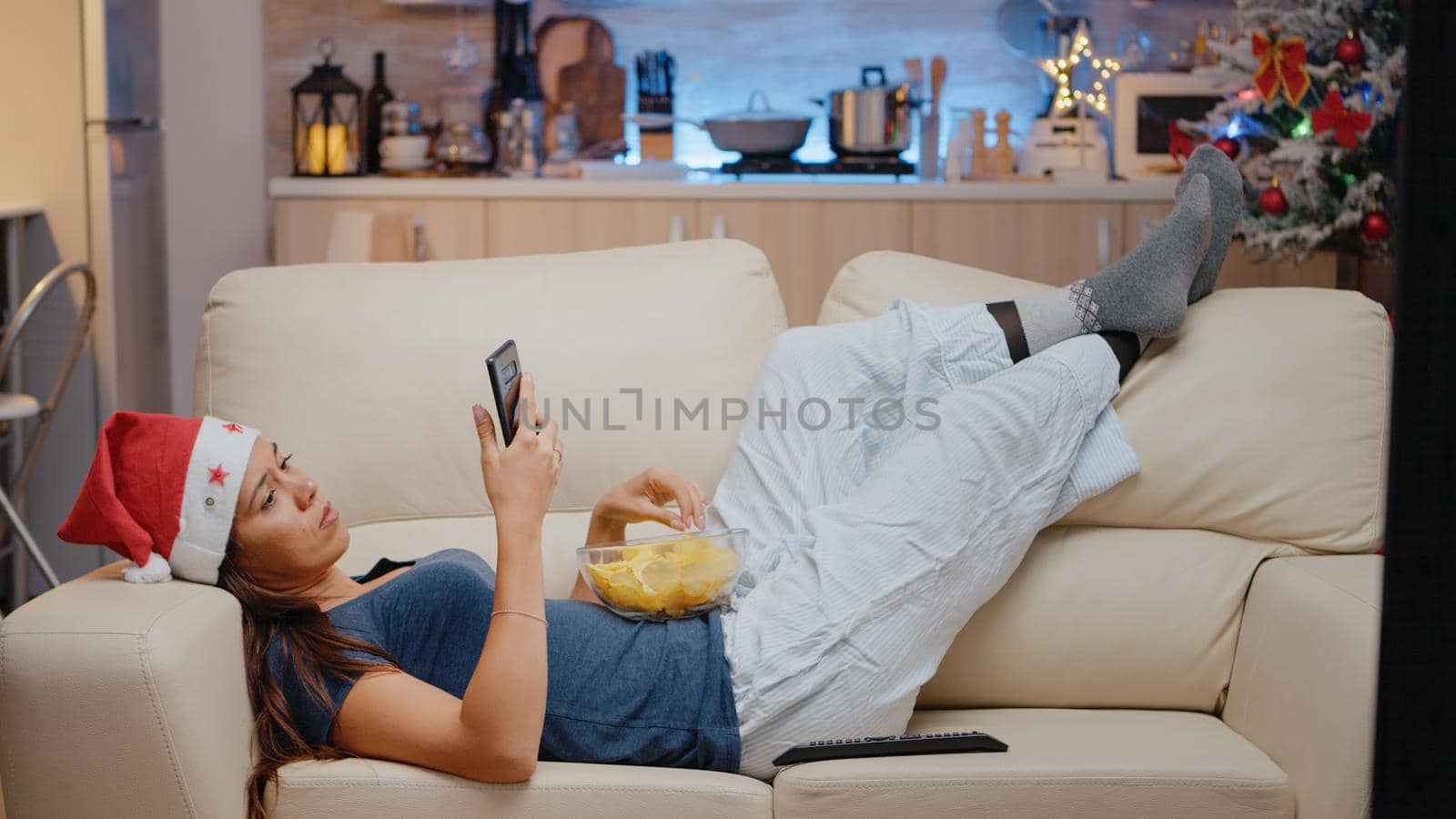 Woman browsing internet on smartphone and watching television by DCStudio