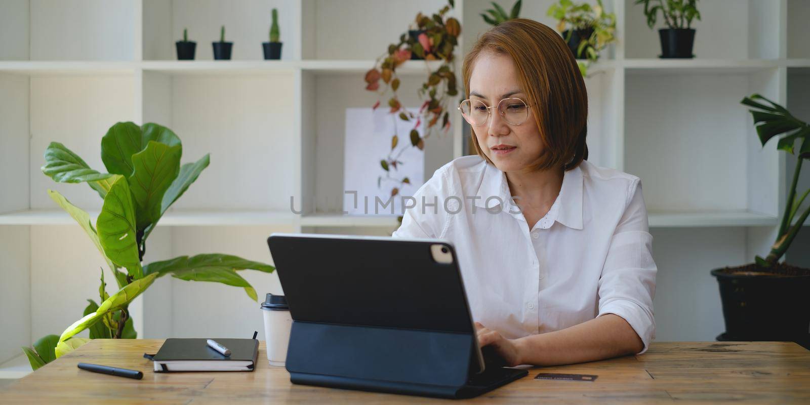 Adult woman focusing and try to using stock trading on digital tablet application. trade, stock, invest concept. by itchaznong