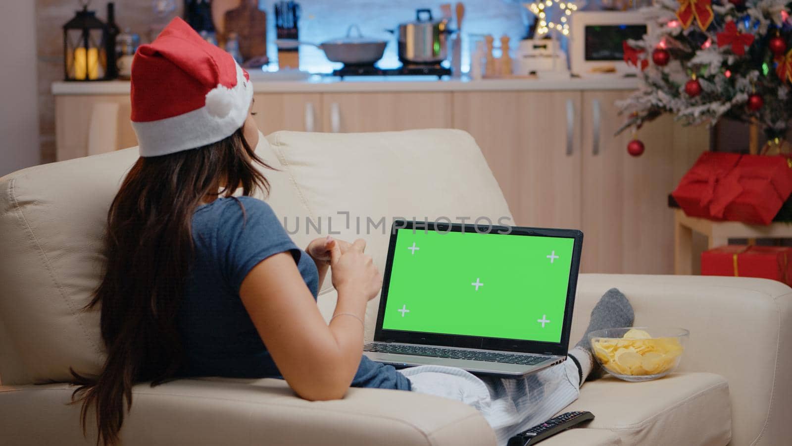 Woman talking and using horizontal green screen on laptop. Adult with santa hat watching isolated template and mockup background on gadget with chroma key. Device with technology