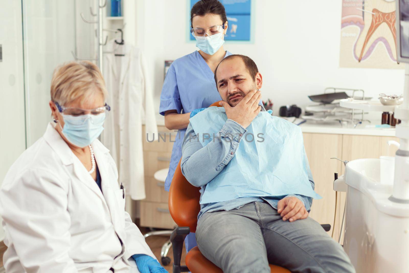 Man patient putting his hand on cheek showing toothache complaining about tooth pain by DCStudio