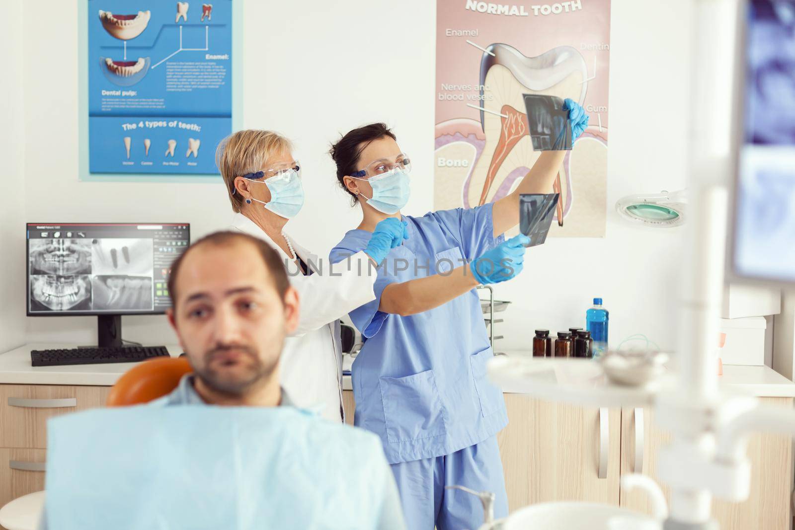 Man patient sitting on dental chair waiting for dentist doctor examining tooth radiography during stomatology appointment. Medical team checking toothache treatment working in dentistry clinic office