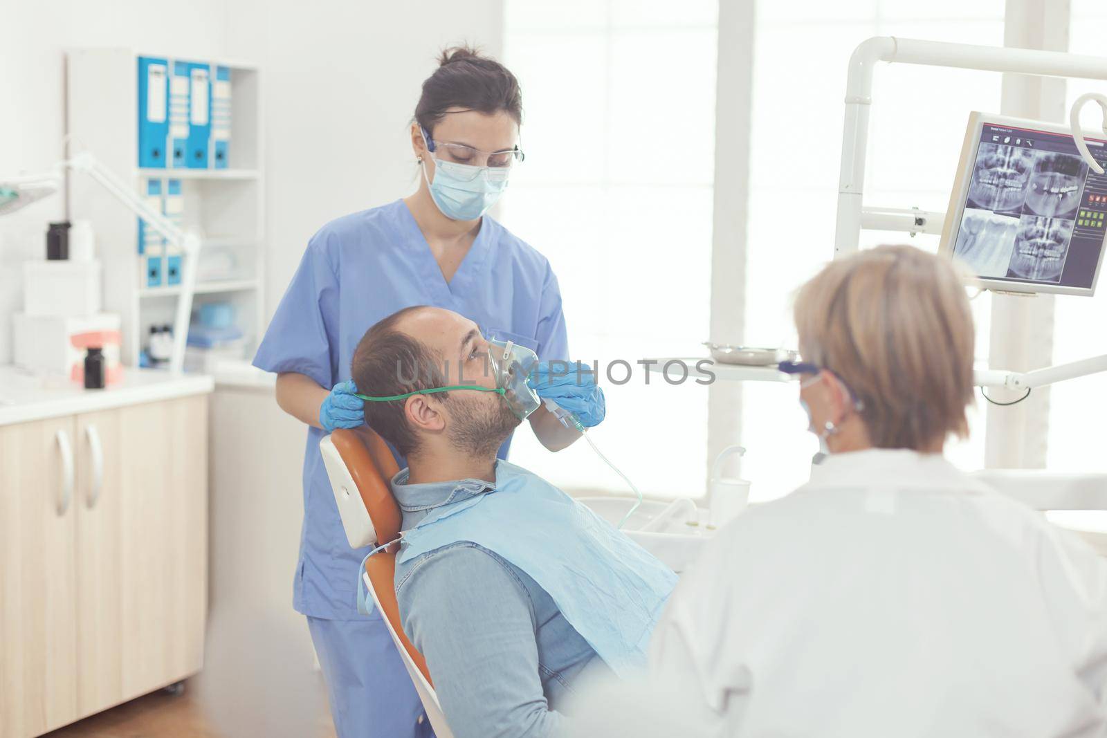 Stomatologist nurse putting oxigen mask to patient examining toothache by DCStudio