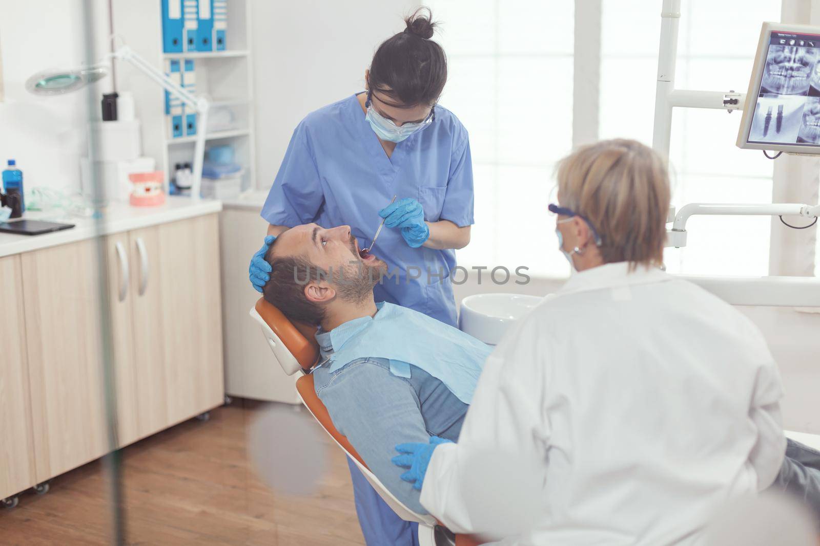 Medical assistant analyzing mouth of sick patient preparing for dental surgery while working in stomatology clinic office. Stomatological doctor waiting for tooth inspection