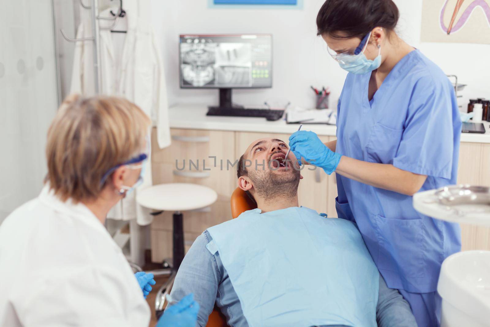Hospital nurse in medical uniform looking into sick pacient mouth analyzing teeth health preparing for stomatological surgery. Stomatologist doctors working in orthodontic clinic