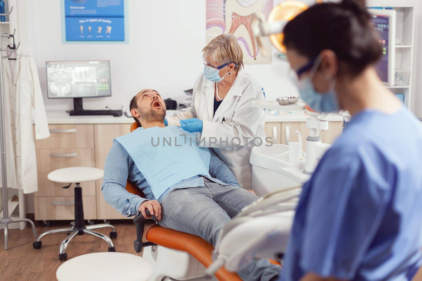 Sick patient sitting on dental chair with open mouth by DCStudio