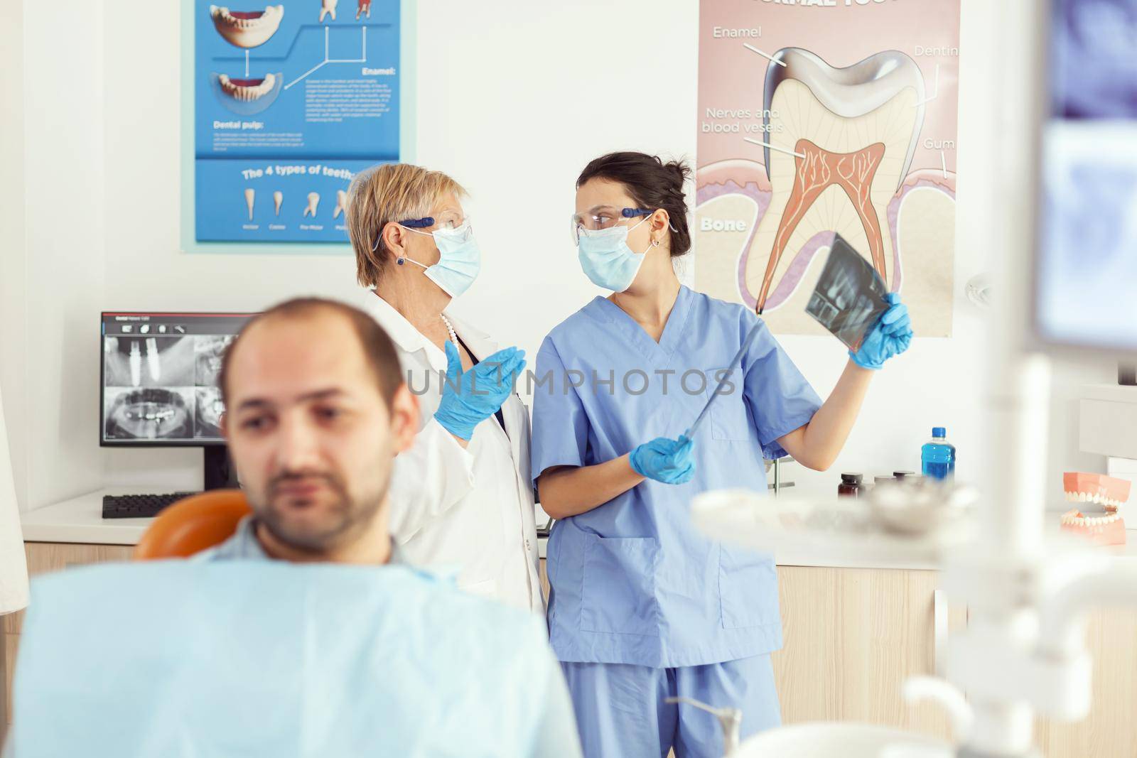 Stomatologist doctor and orthodontist assistant examining teeth radiography by DCStudio