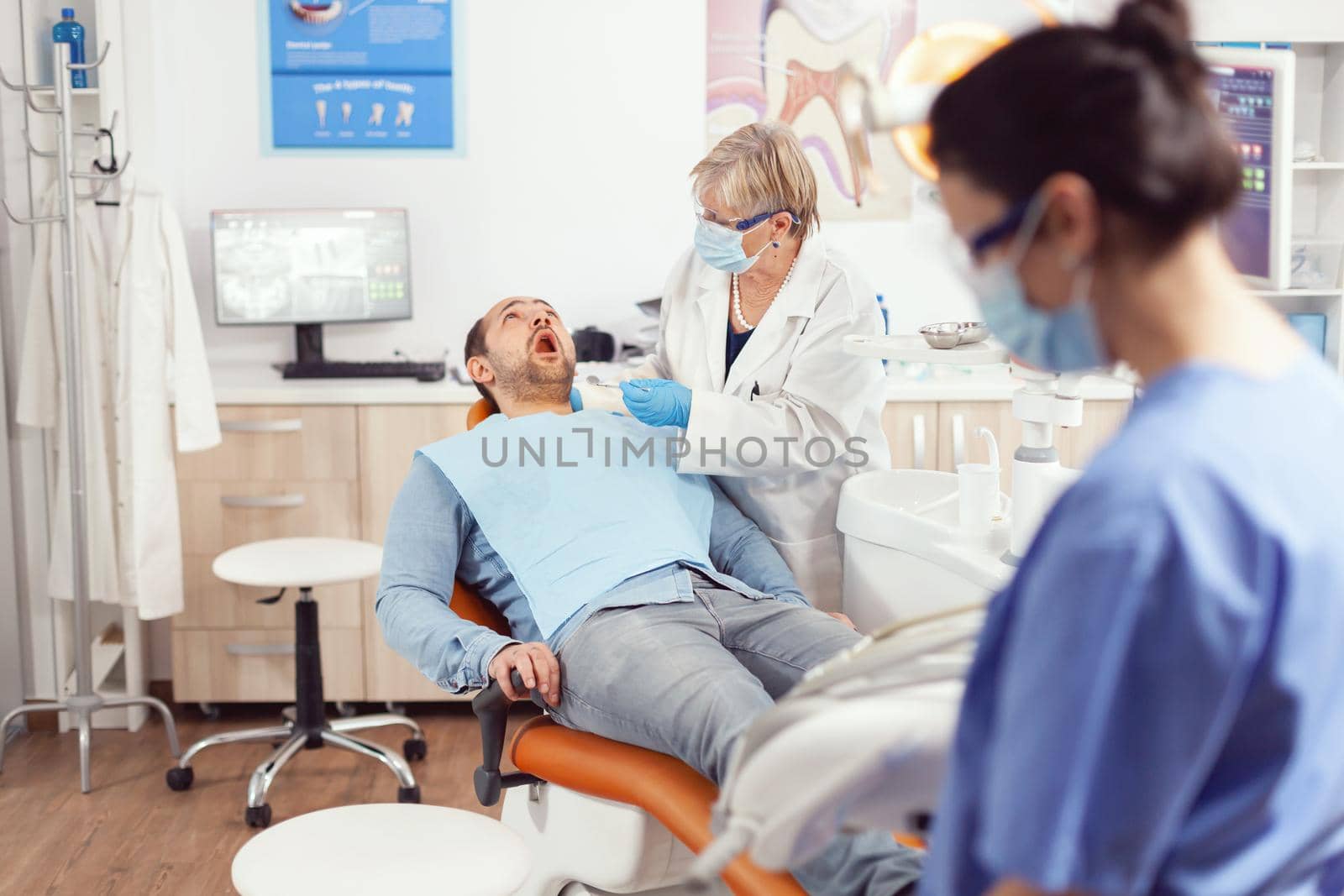Stomatologist senior doctor looking in patient mouth preparing for stomatology inspection. by DCStudio