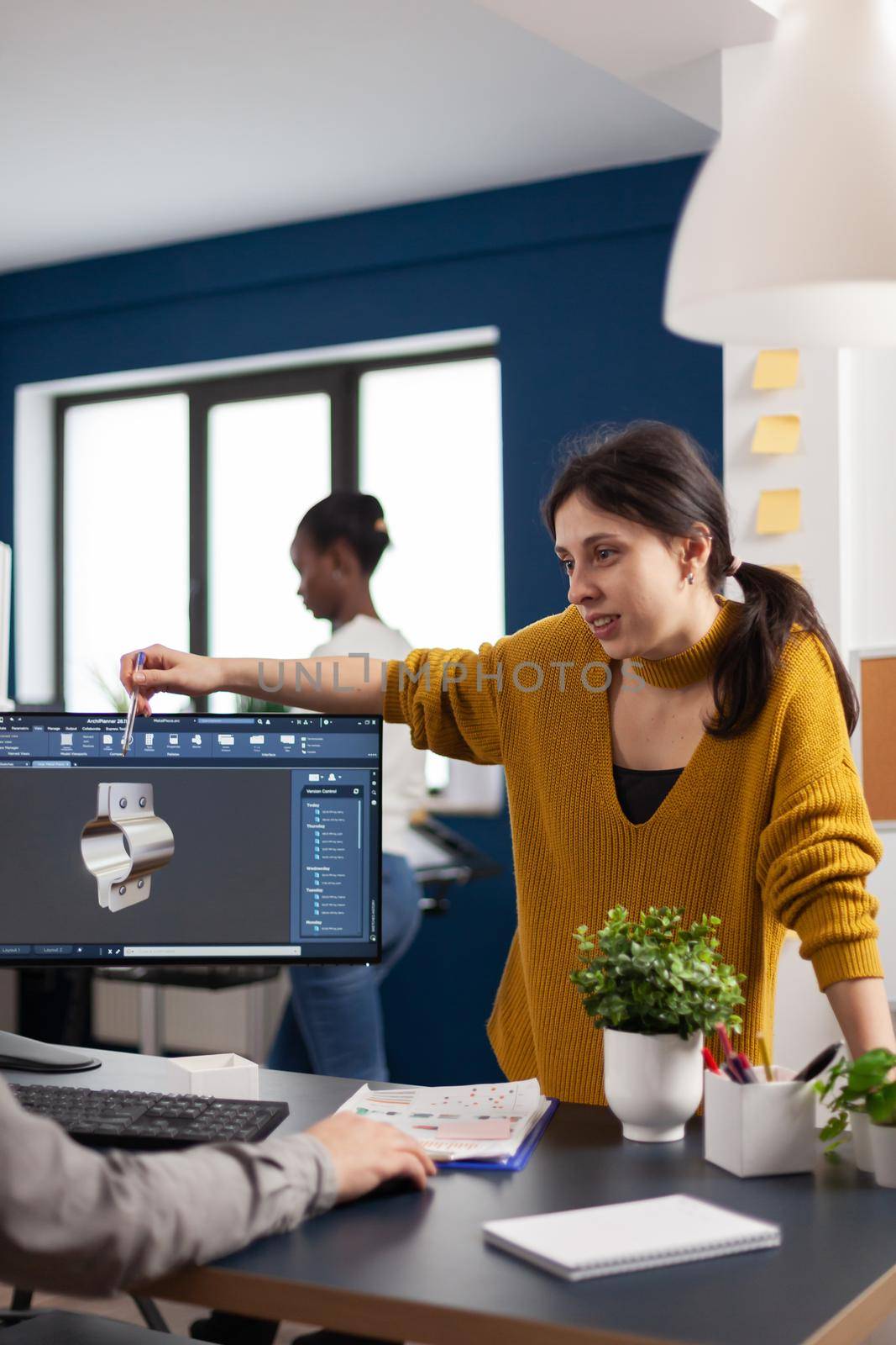 Team discussing about industrial project using dual monitors setup to desing 3D gears and metalic clamp in CAD software. Woman industrial engineer project manager working in creative office