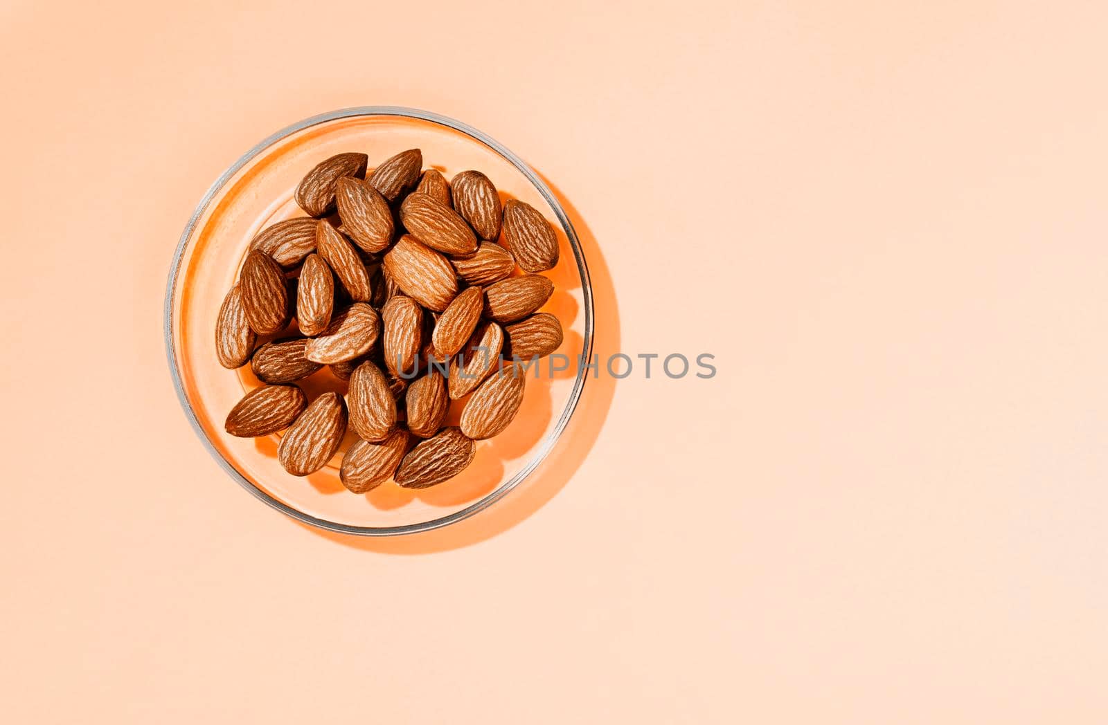 Heap of brown shelled almonds on glass plate