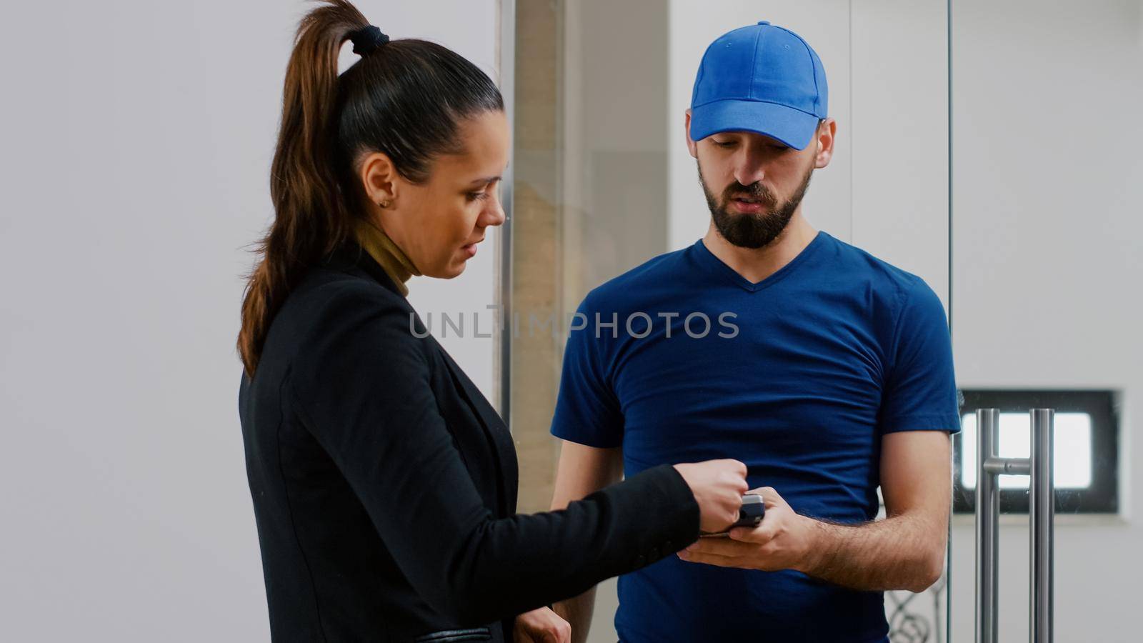 Delivery guy bringing takeaway food meal holding POS terminal service in startup business company office. Businesswoman receiving lunch order paying with contactless credit card during lunchtime