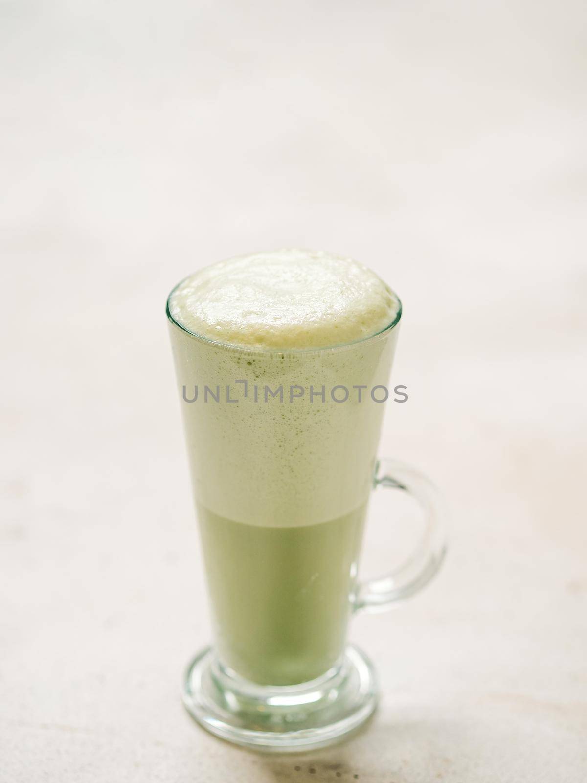 Matcha green tea latte in glass. Matcha latte on light background. Copy space. Vertical Vertical.