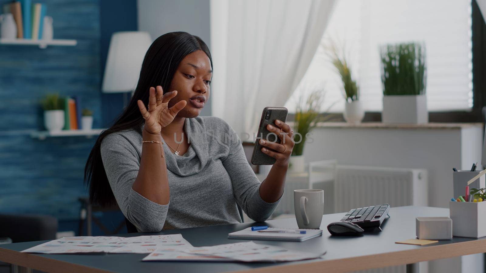 Black student chatting with math professor explaining online maths lesson using university platform sitting at desk in living room. African woman having online videocall meeting conference working remote