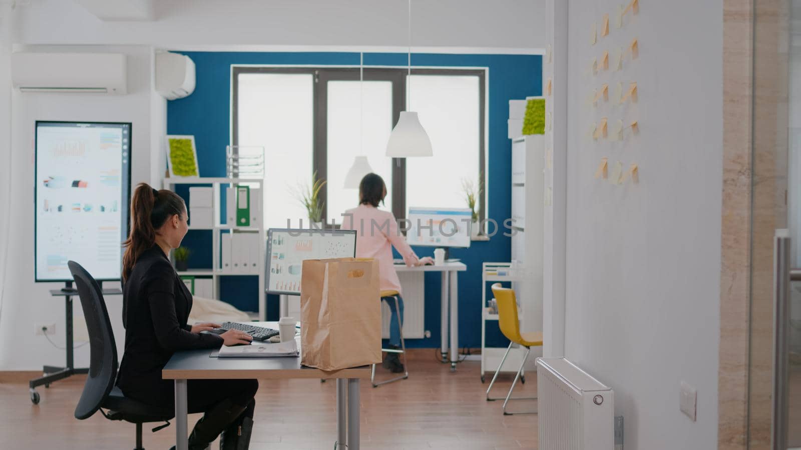 Cheerful delivery guy giving takeaway fastfood meal order to businesswoman during takeout lunchtime in company office. Manager receiving delivery food package working at marketing strategy