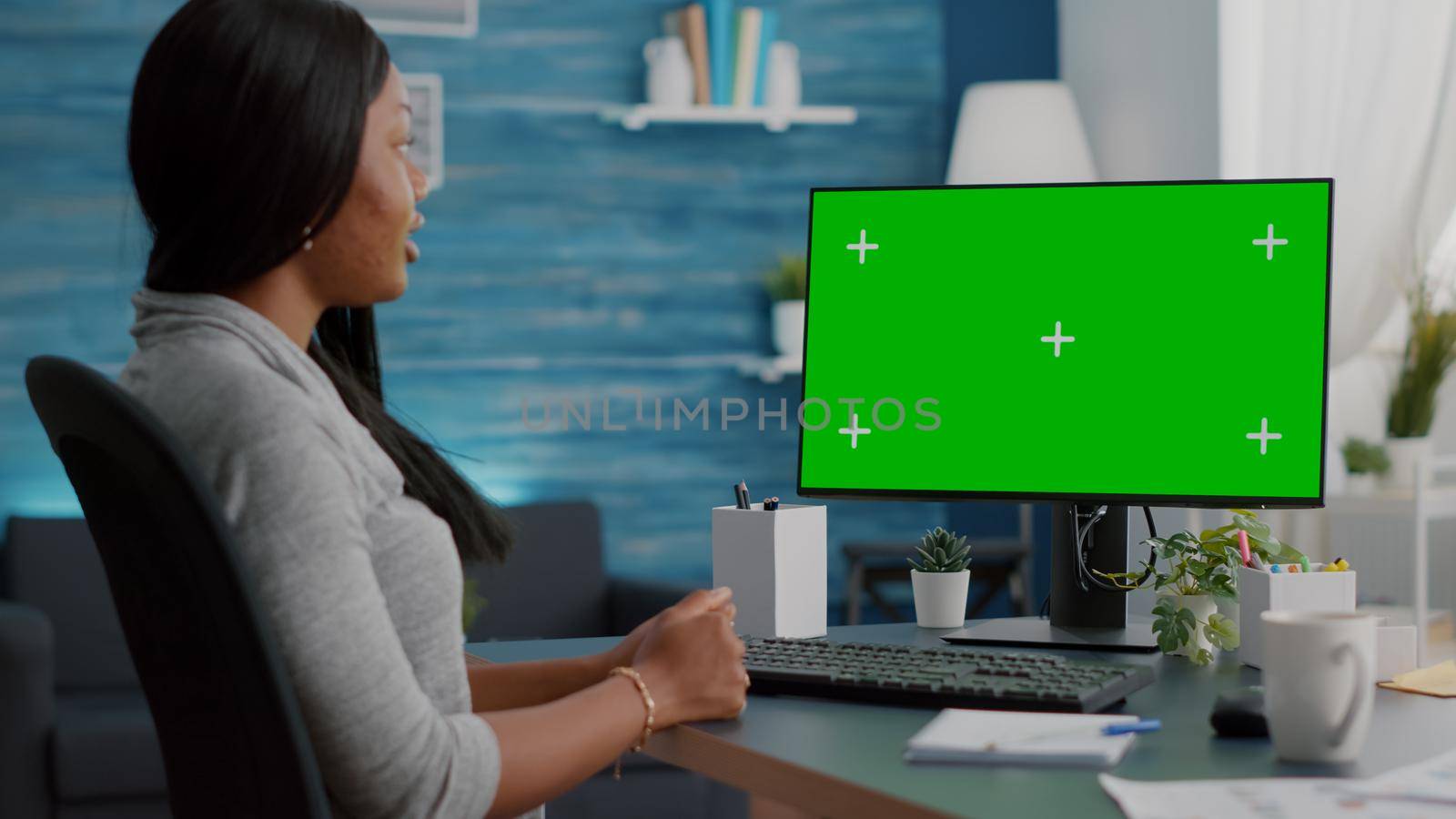 African student talkingwith school professor during online videocall meeting conference looking at mock up green screen chroma key computer with isolated display. Black woman working remote from home